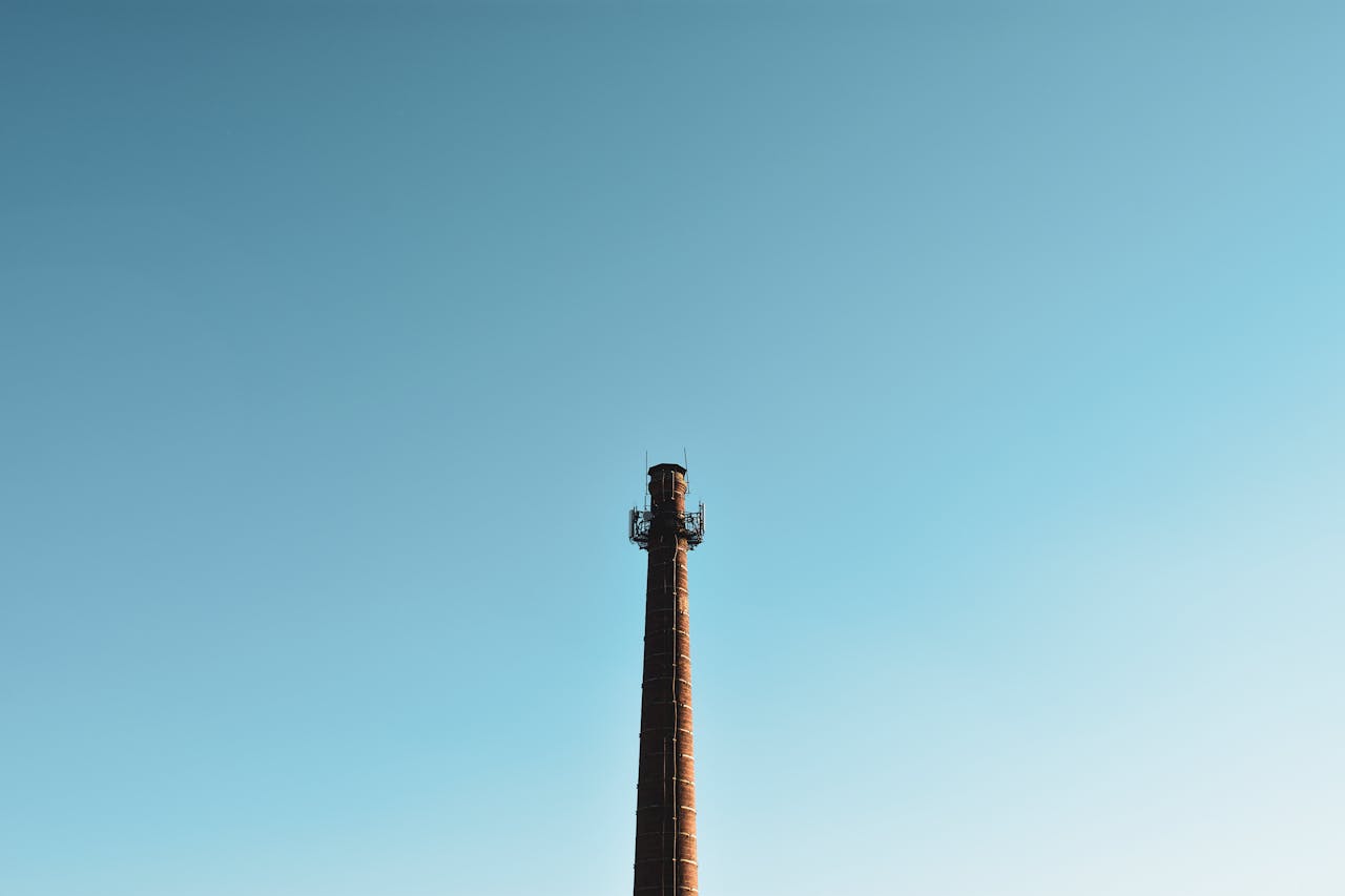 Tall industrial chimney against a clear blue sky, perfect for industry themes.